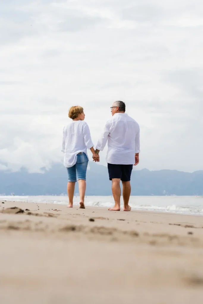 Older couple holding hands walking on the beach